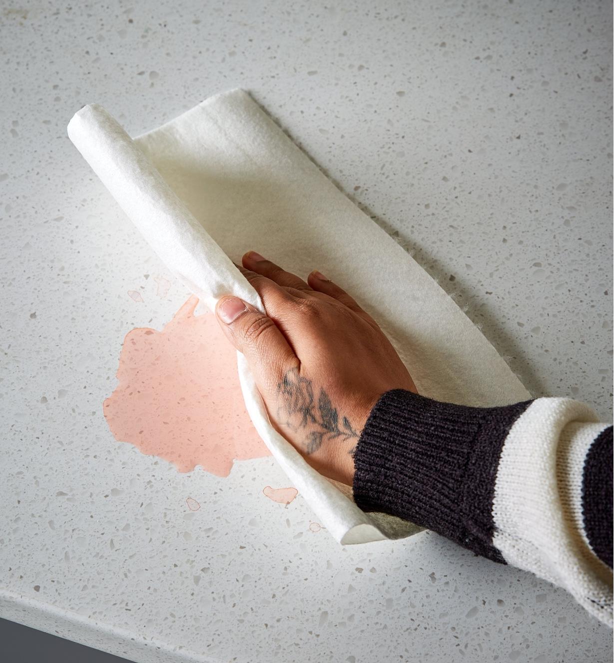 Wiping up a spill on a countertop using a reusable tear-off towel
