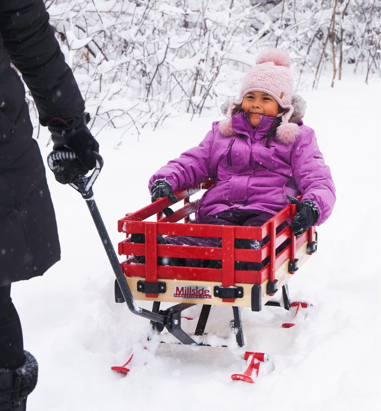 A child in an all-season wagon being pulled through the snow