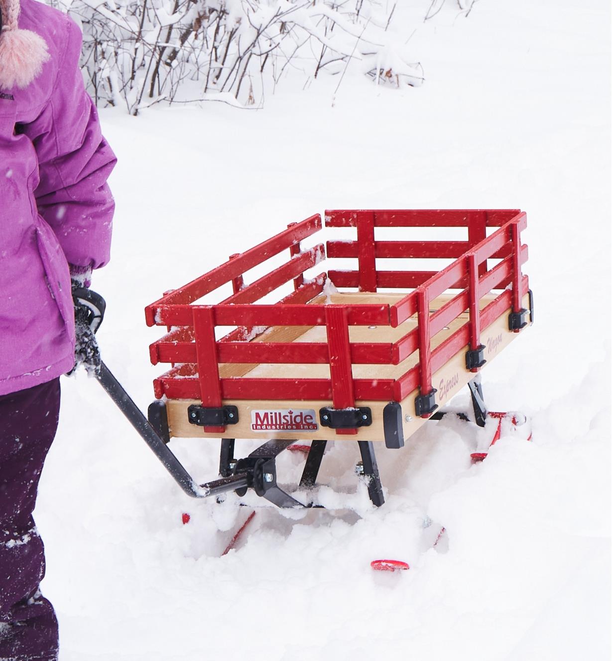 A young girl pulls an all-season wagon through the snow