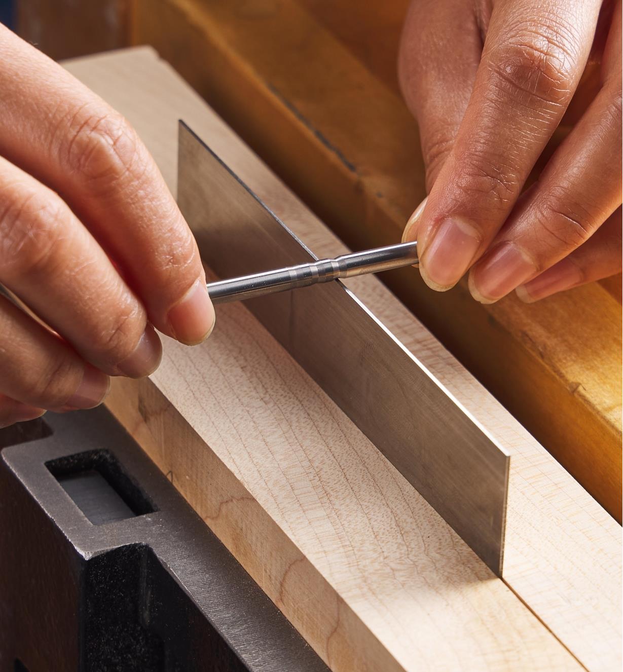 Using a burnishing rod to burnish 15° hooks on the edge of a straight scraper clamped in a vise