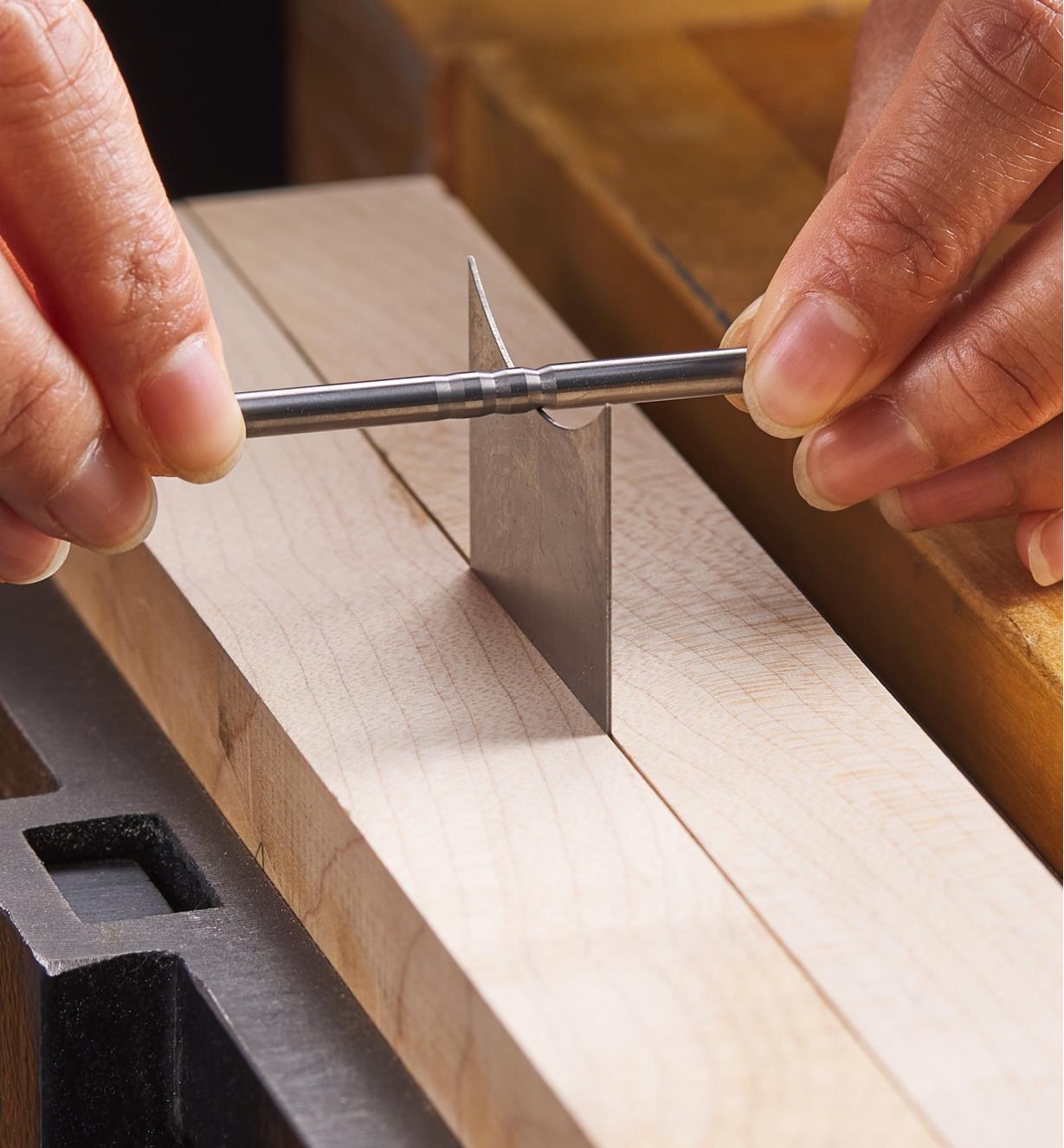 Using a burnishing rod to burnish 15° hooks on the concave edge of a scraper clamped in a vise