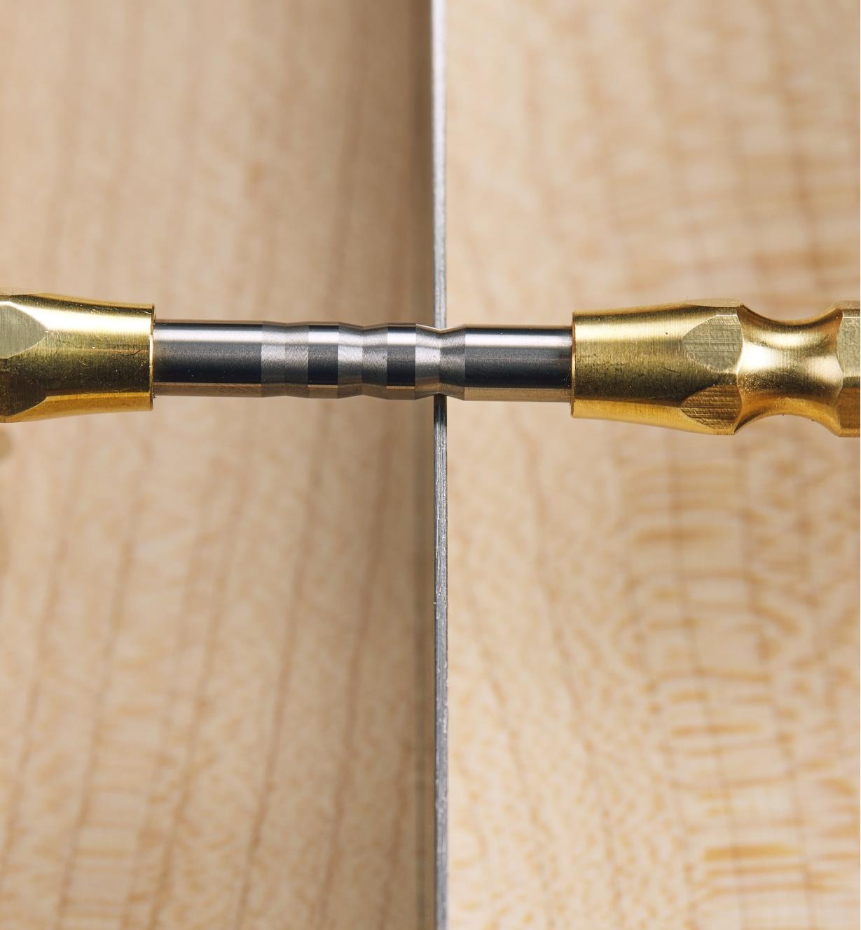 A close-up view of an Accu-Burr handled burnisher rolling 15° hooks on the edge of a scraper