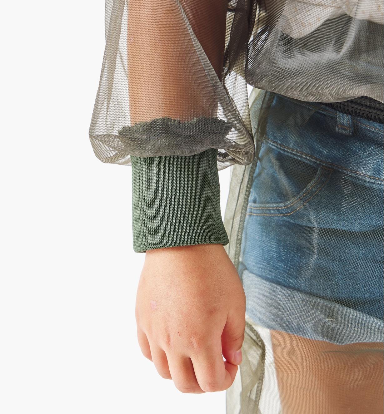 A close-up view of a full-width rib-knit wrist cuff on a hooded bug-protection shirt worn by a child