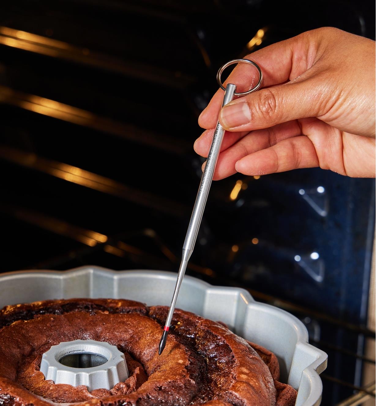 A cake tester with a black tip being inserted into a Bundt cake