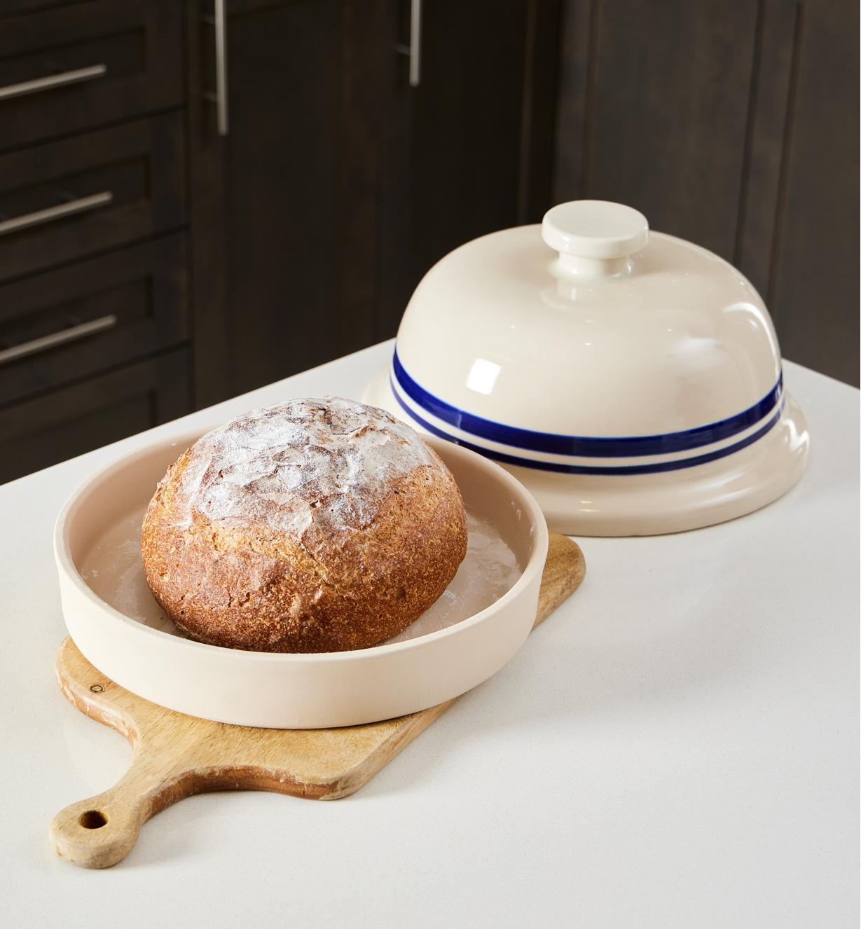 A baked sourdough loaf sits in the base of the bread-baking cloche