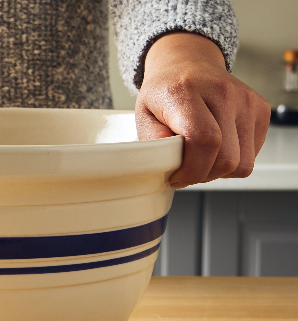 Close-up view of a hand gripping the lip of the Dominion mixing bowl