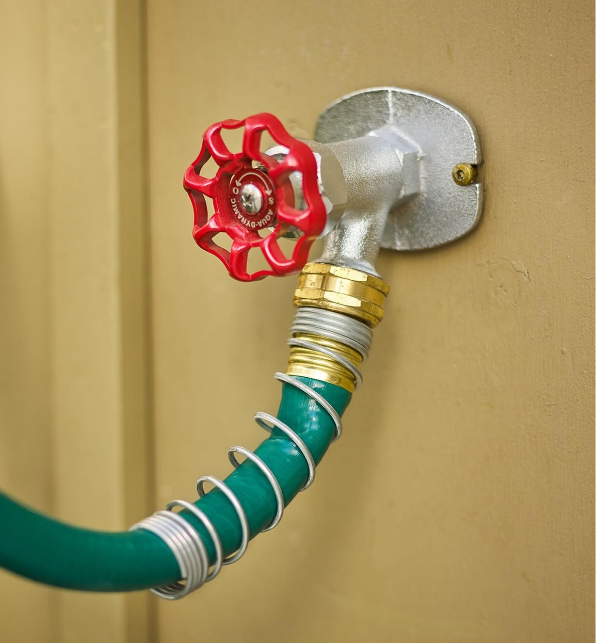 A hose with a spring collar connected to an outdoor tap