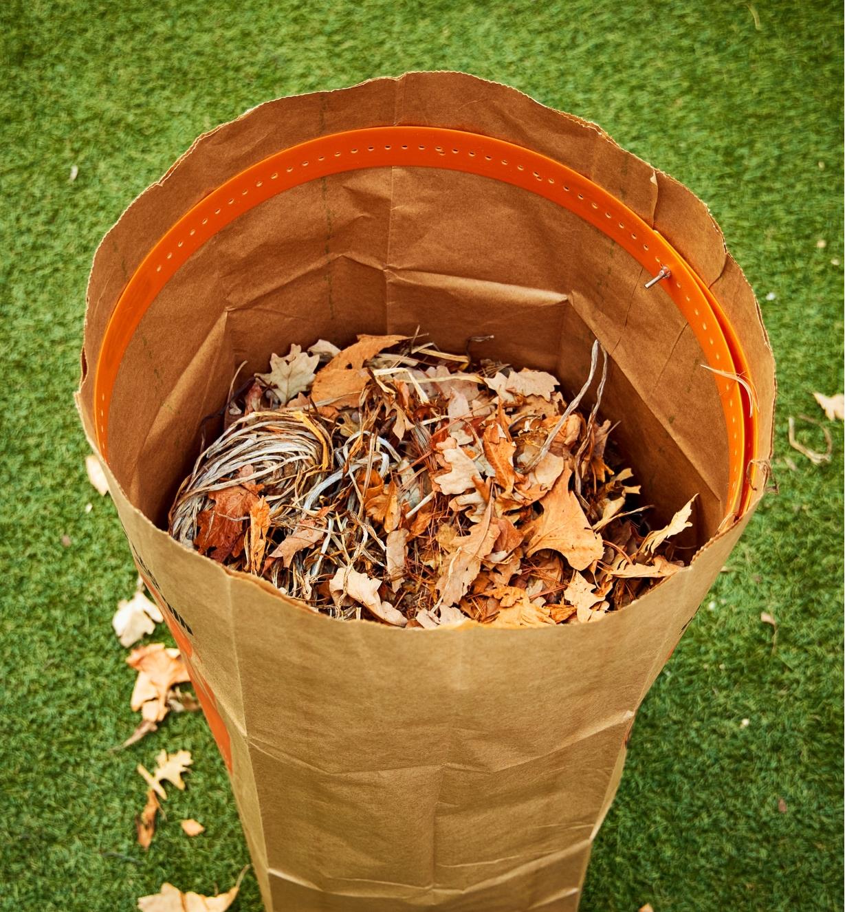 A large paper bag filled with leaves held open by a leaf bag ring