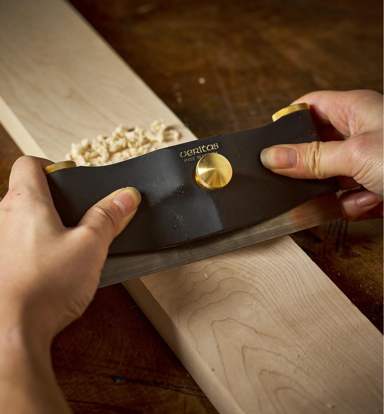 Scraping a wood piece with a scraper held in a  a Veritas scraper holder