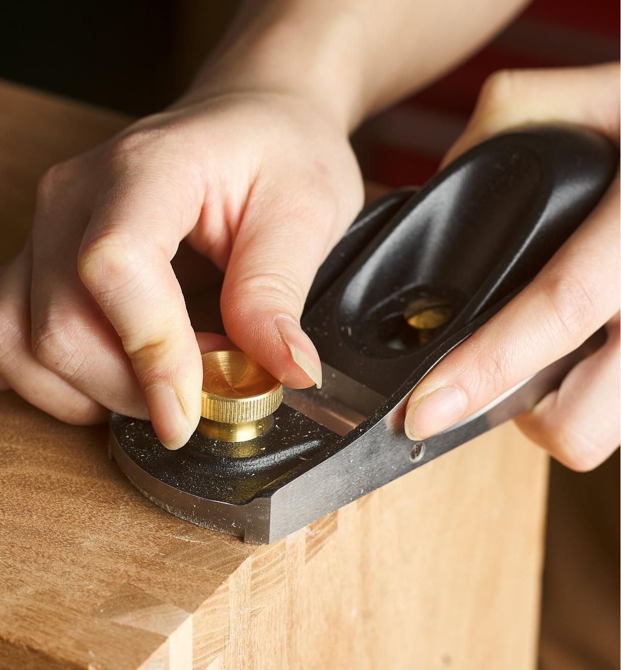 Adjusting the brass front knob on a low-angle block plane on a table edge