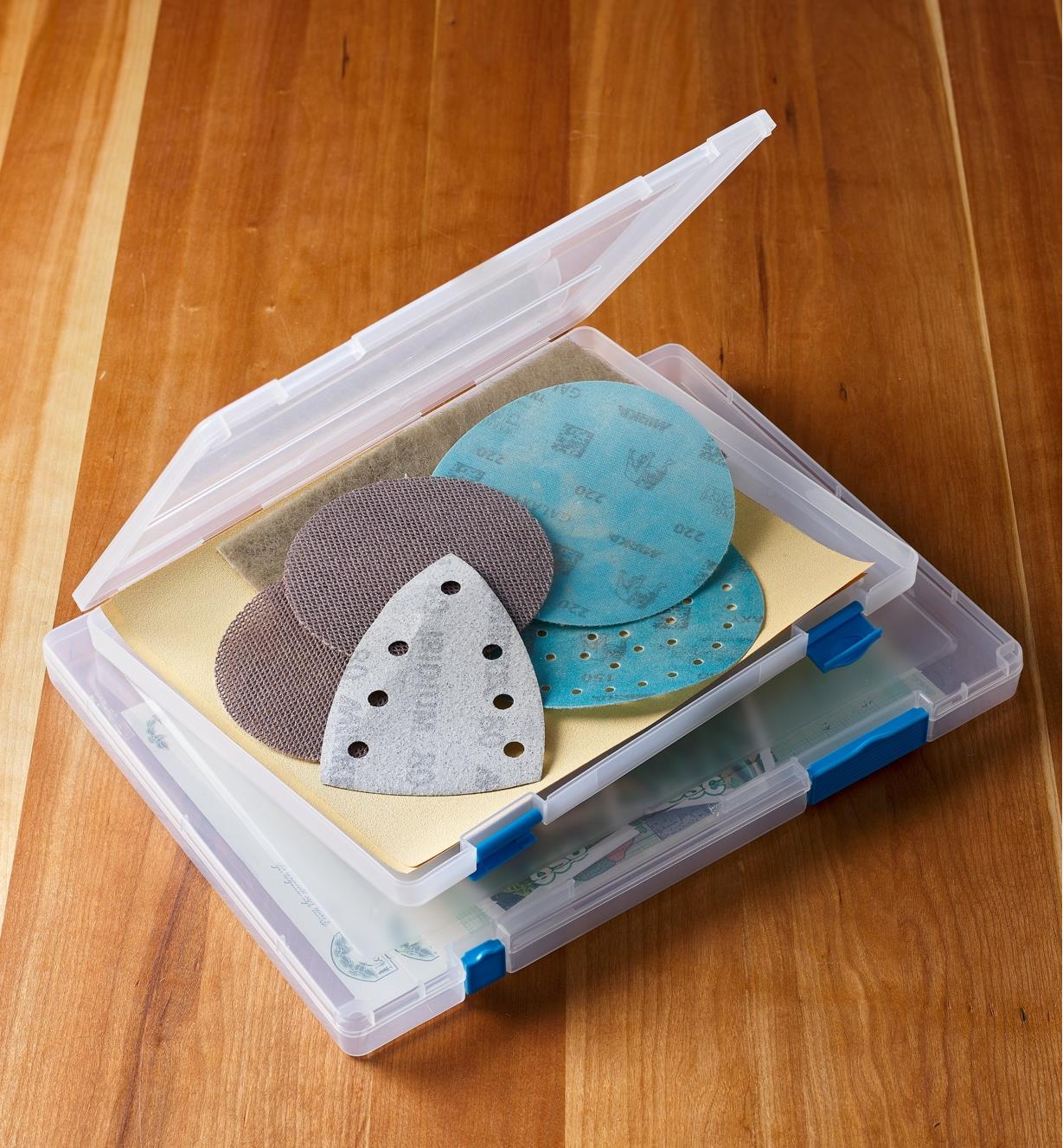 A legal-size case full of sandpaper and other abrasives set on a letter-size case holding seed packs