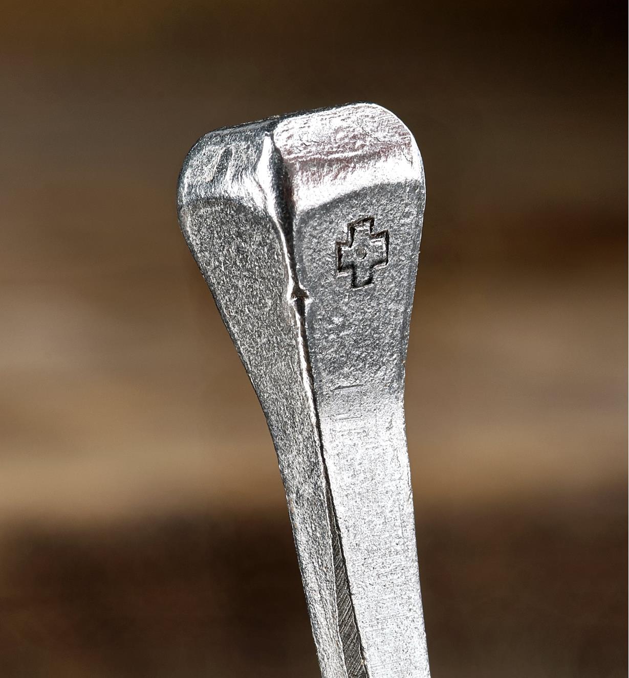 A close view of the Swiss cross embossed on the side of a #9 horseshoe nail