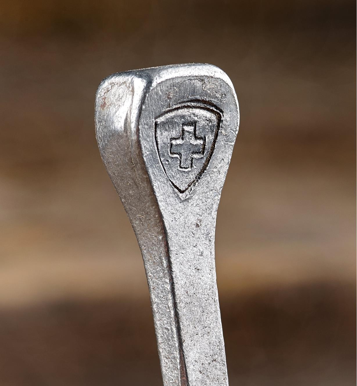A close view of the Swiss cross and shield embossed on the side of a #10 horseshoe nail