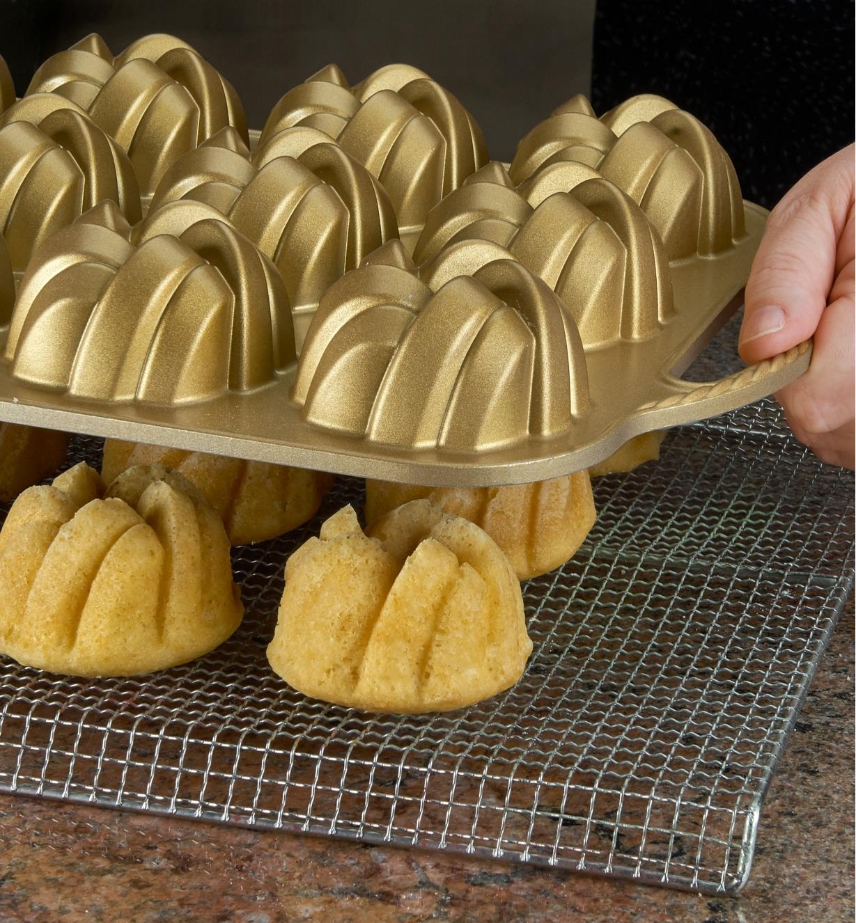 Tipping freshly baked mini Bundt cakes out of the pan onto a rack to cool