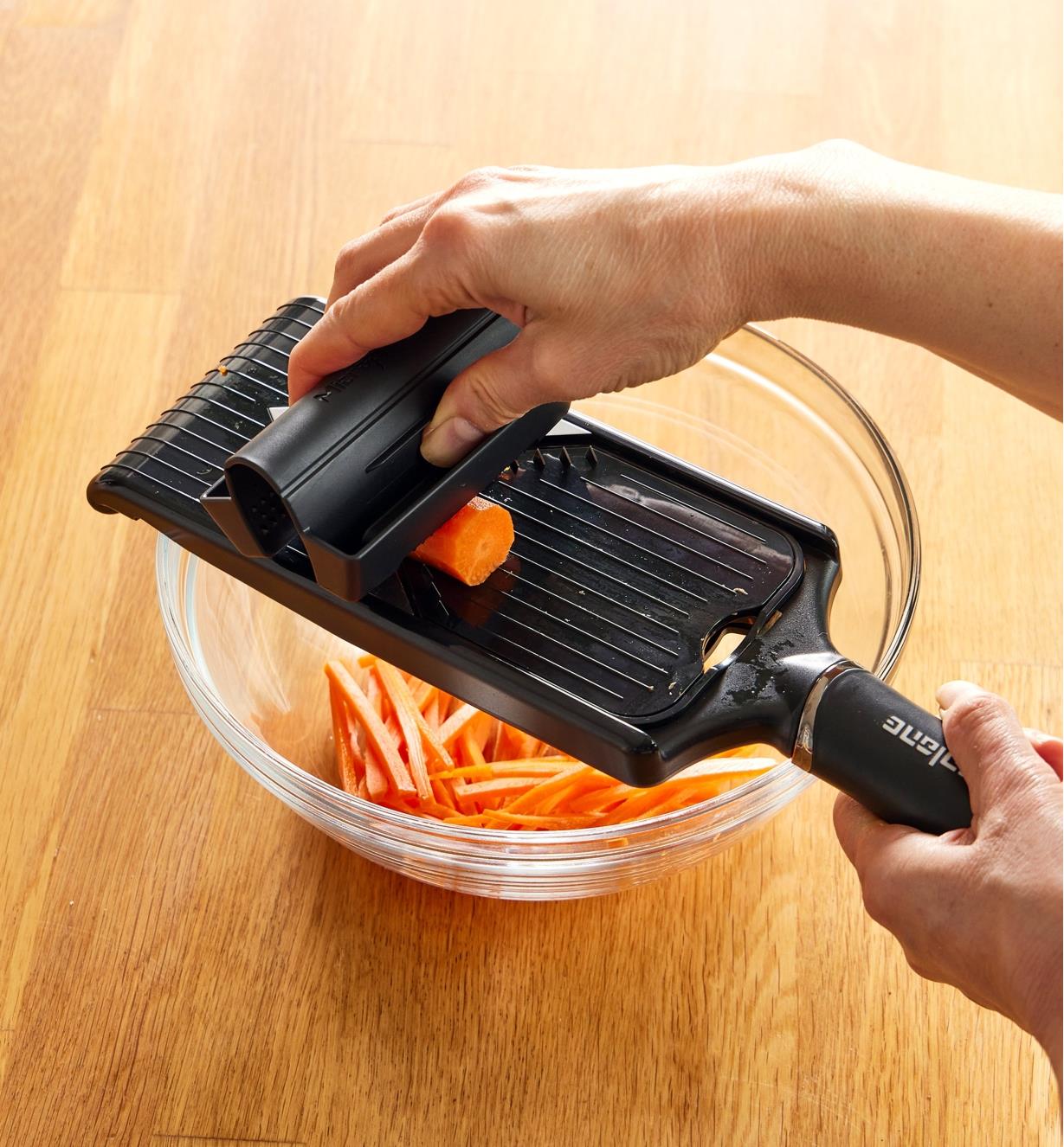Julienning a carrot directly into a bowl using the V-slicer with julienne blade