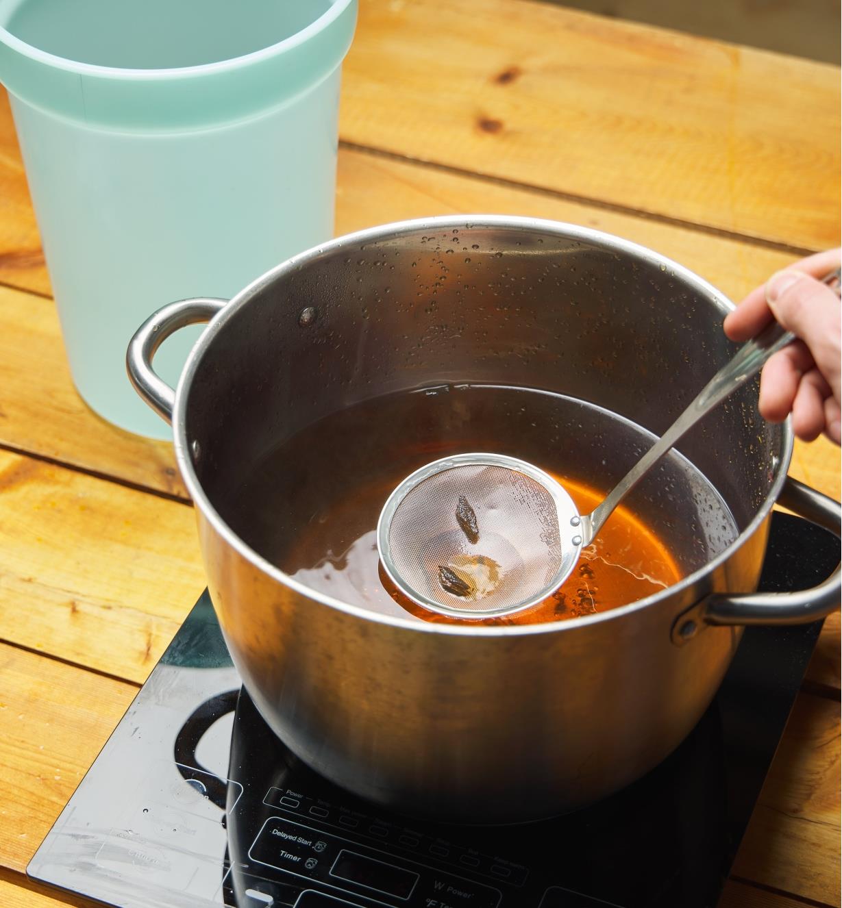 Removing herbs from a pot of liquid using a fine mesh skimming ladle