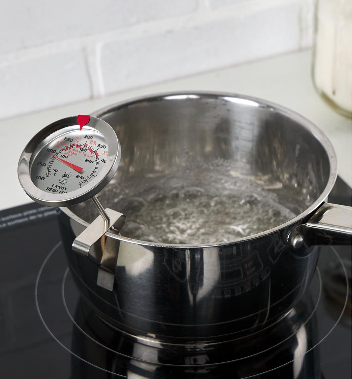 Thermomètre pour friture et confiserie accroché à une casserole posée sur une cuisinière