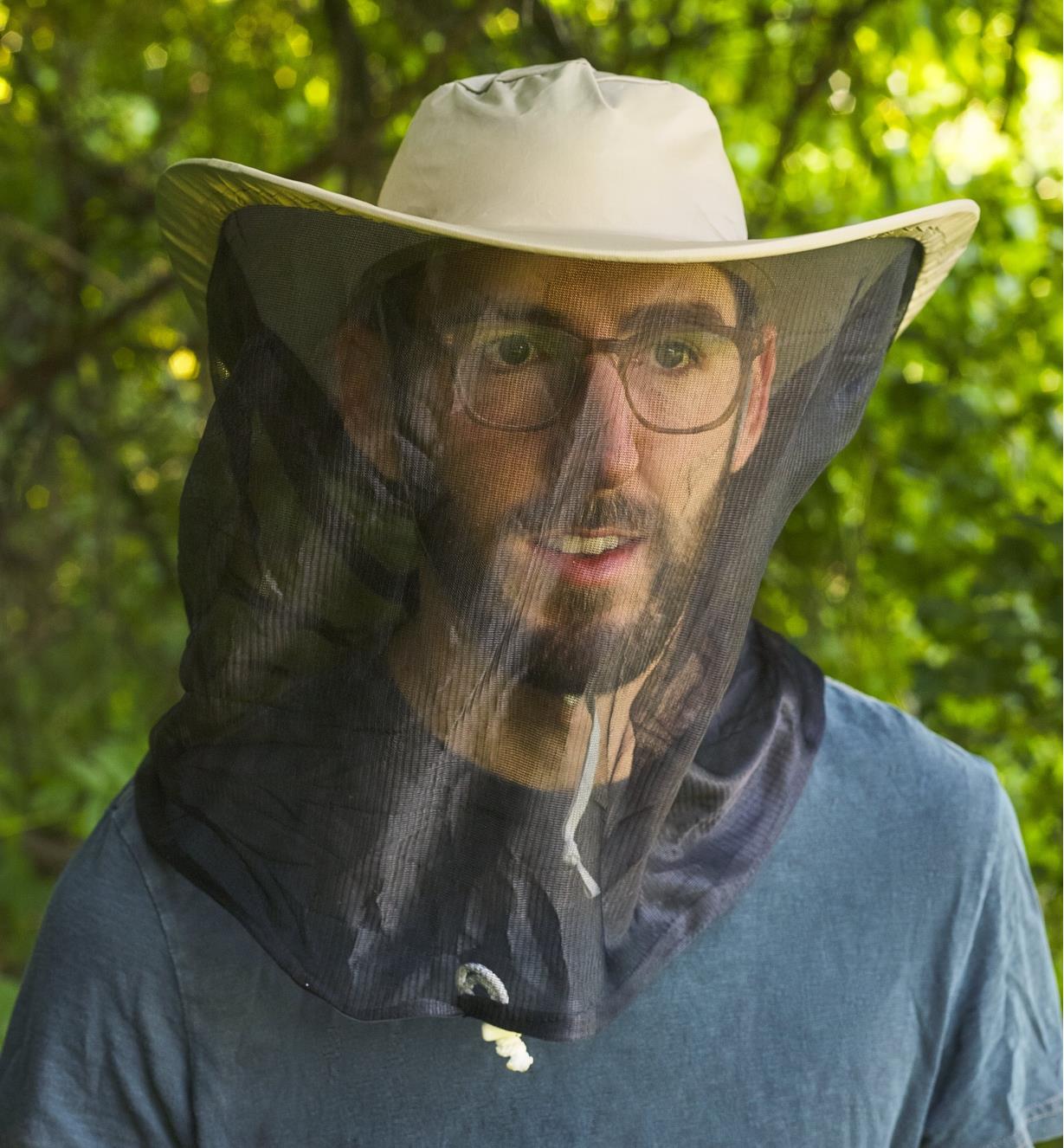 A man wearing a wide-brimmed hat with mosquito netting down over his face