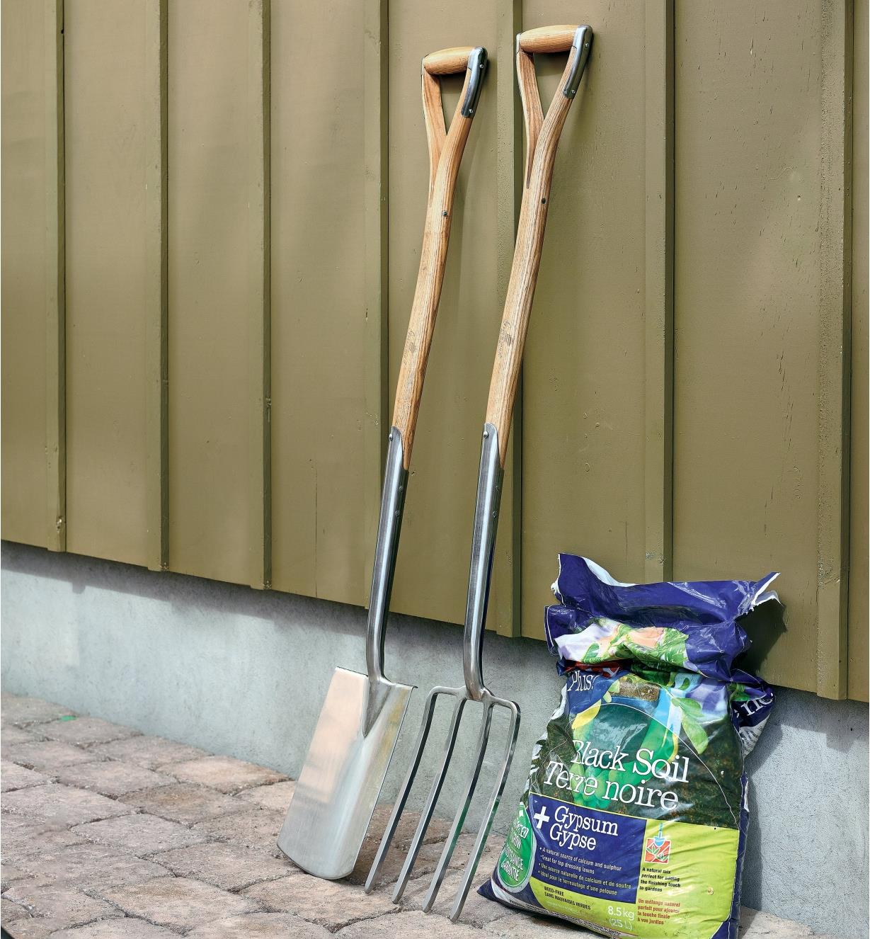 The fork and spade from the ergonomic ash-handled digging spade and fork set lean against a wall