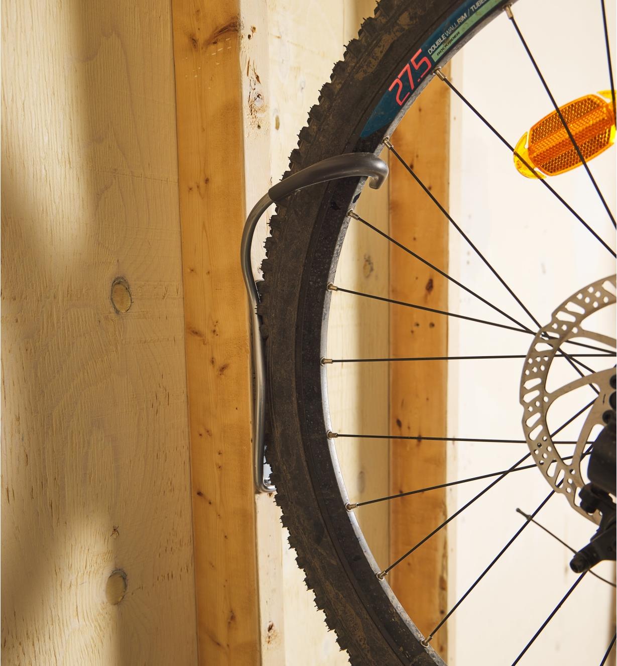 Vue rapprochée d'une roue de vélo retenue par un support vertical pour vélo fixé au mur