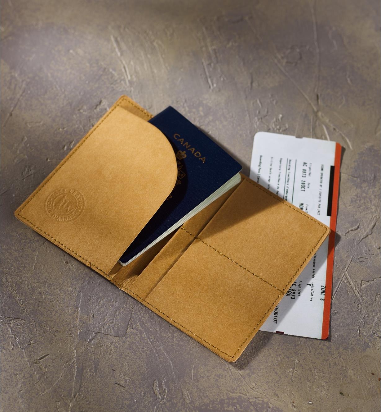 Porte-passeport Tree Leather contenant un passeport déposé sur un billet d’avion sur une table