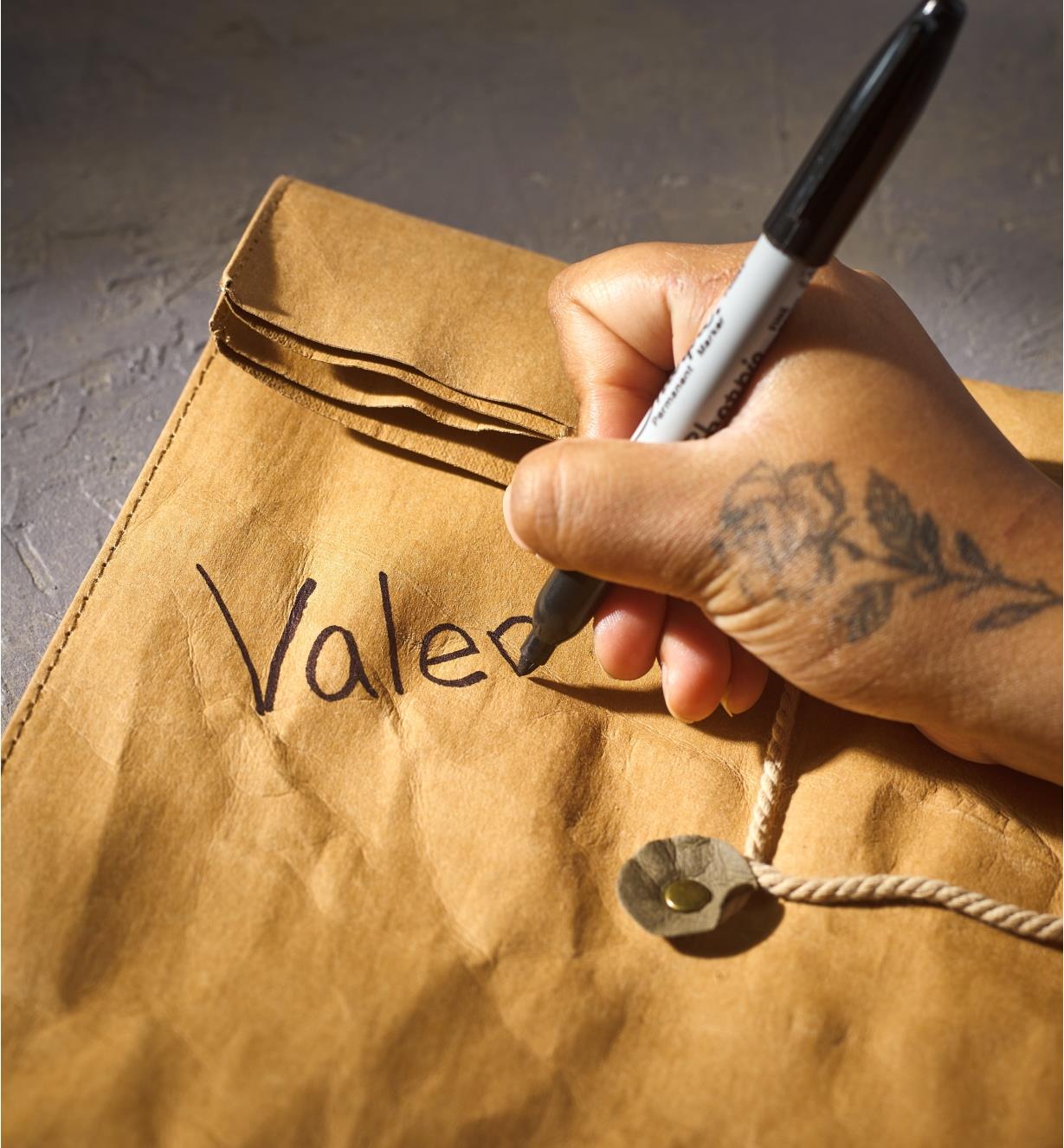 Using a marker to write a name on the tree leather lunch bag