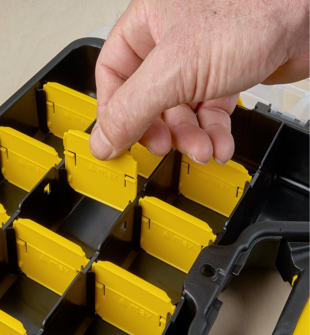 A person inserts a removable divider used to configure the storage spaces in a 9" × 11" clip case