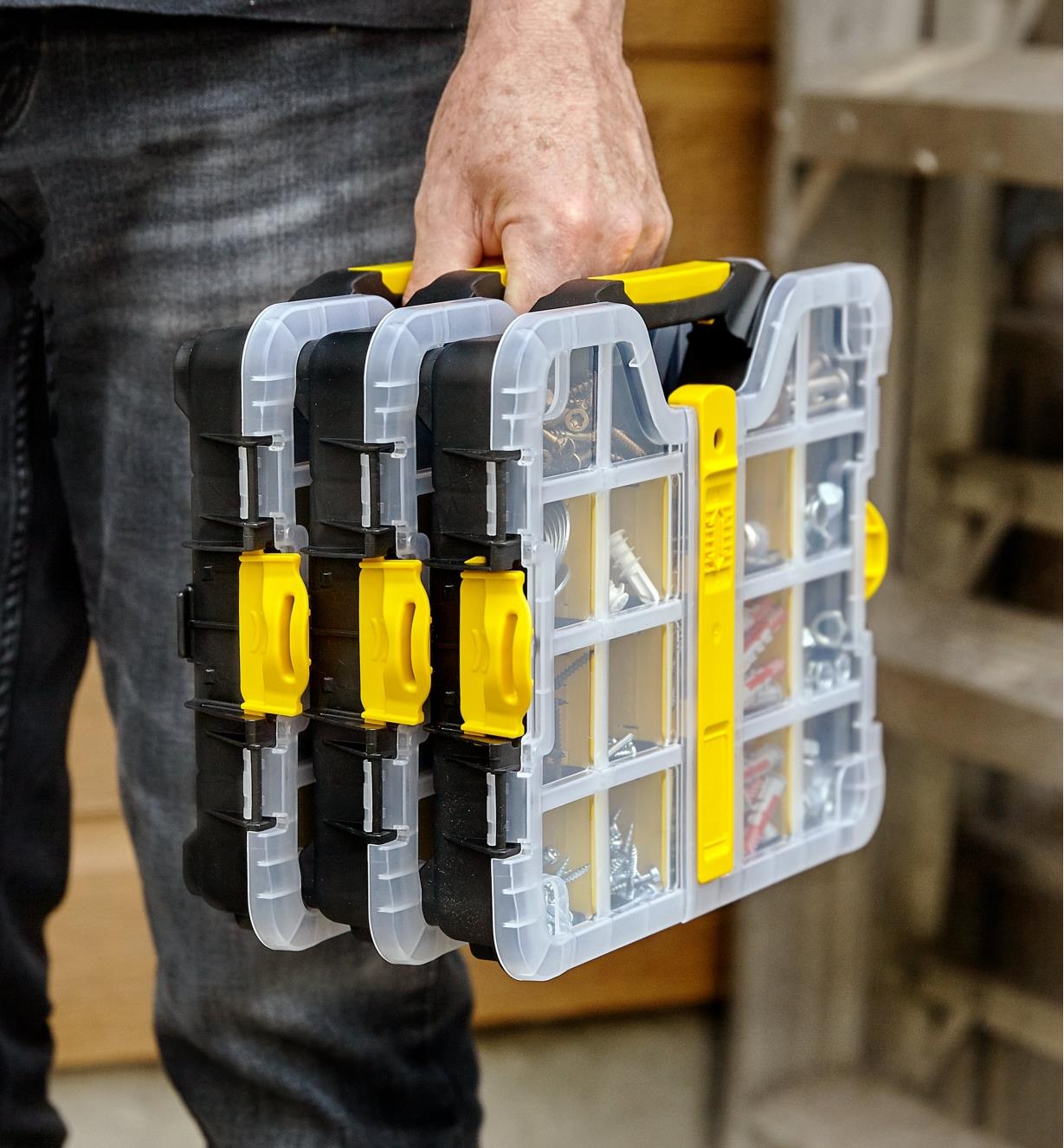A person carries three 9" × 11" cases clipped together and filled with screws and drywall anchors