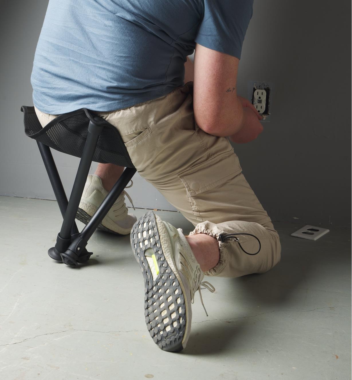 A man seated on a Walkstool doing electrical work
