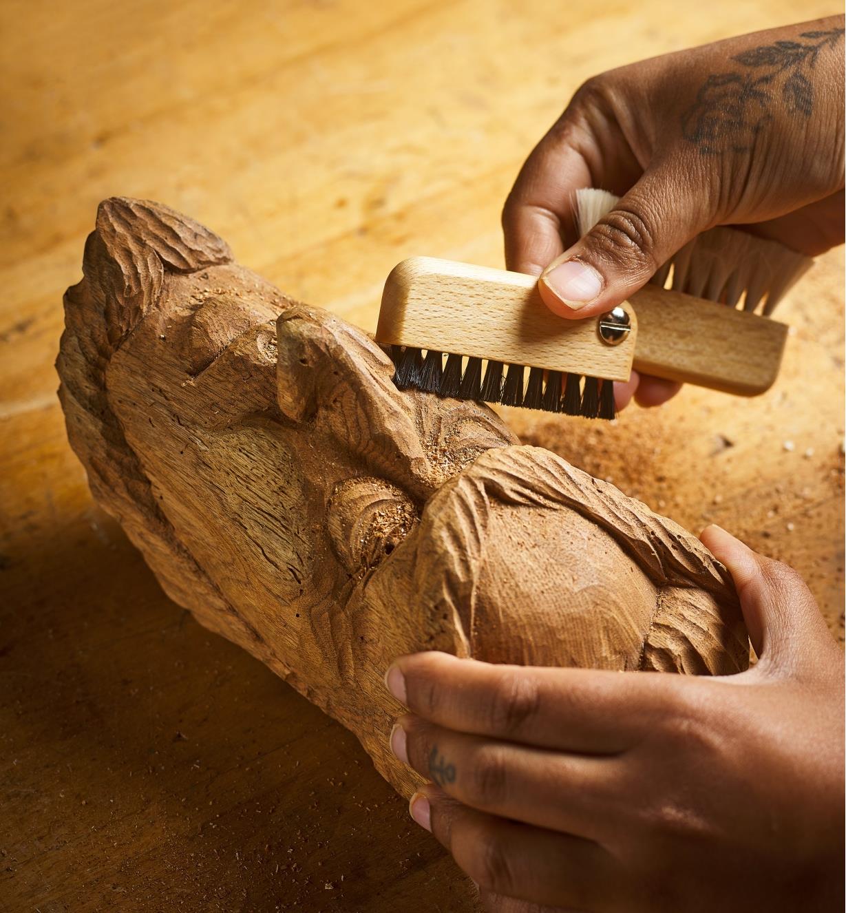 Brushing sawdust from a wood carving using the black bristles of the detail dusting brush