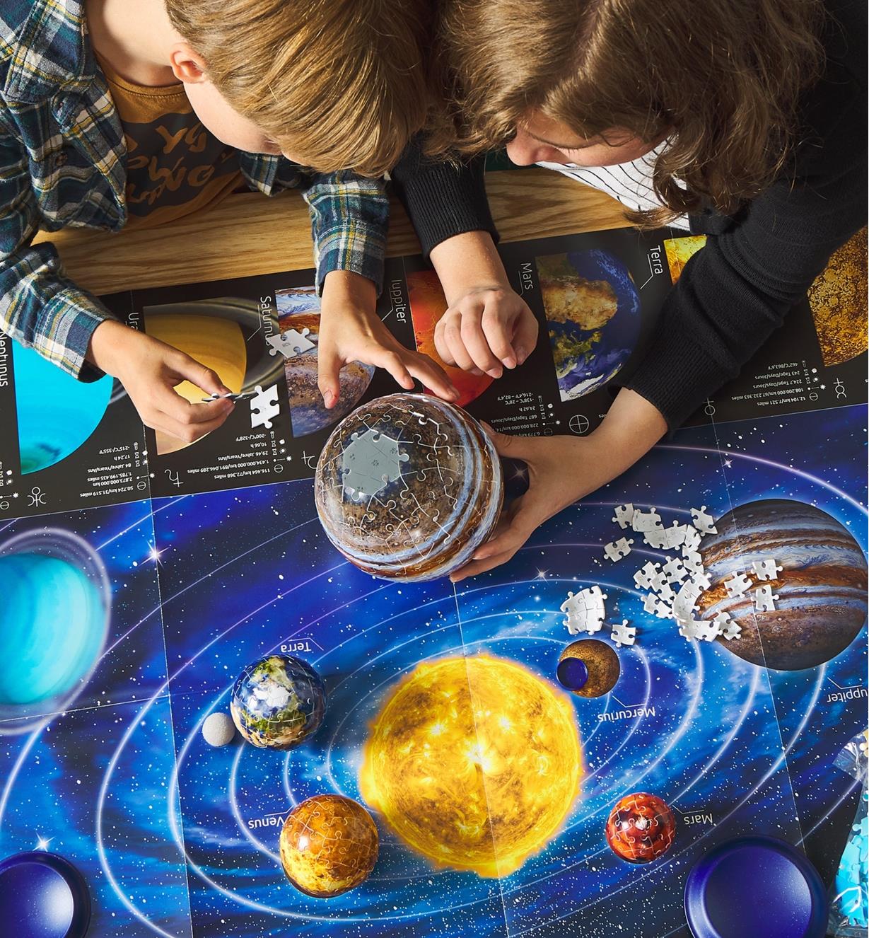 Two children assembling a planet puzzle over a poster of the solar system