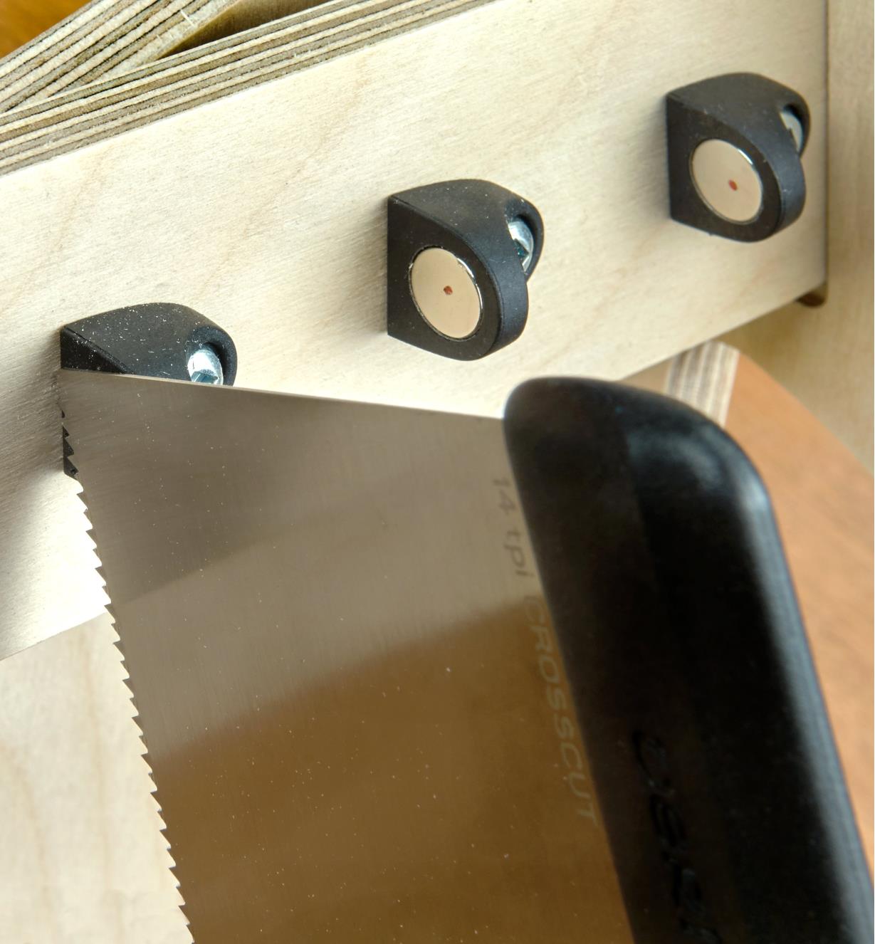A close-up view of a saw blade held by a magnet on the upper frame of a saw till