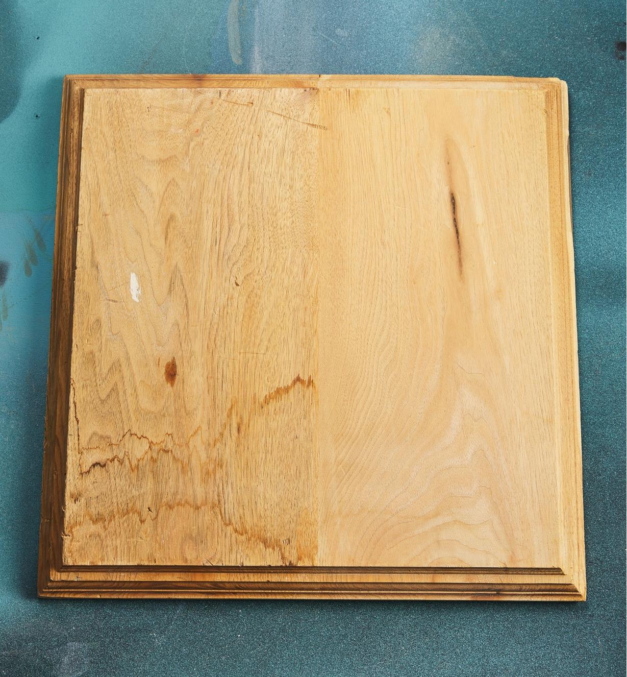 A wooden board with one half dark and stained and the other half light and clean