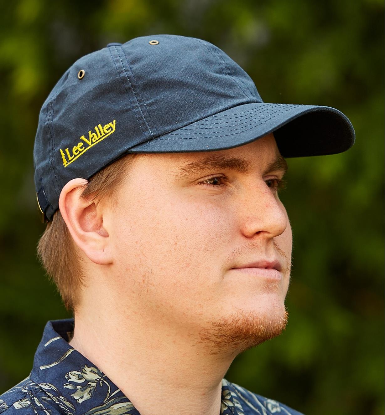 Side view of a model wearing the navy Lee Valley oilskin cap displaying Lee Valley name logo