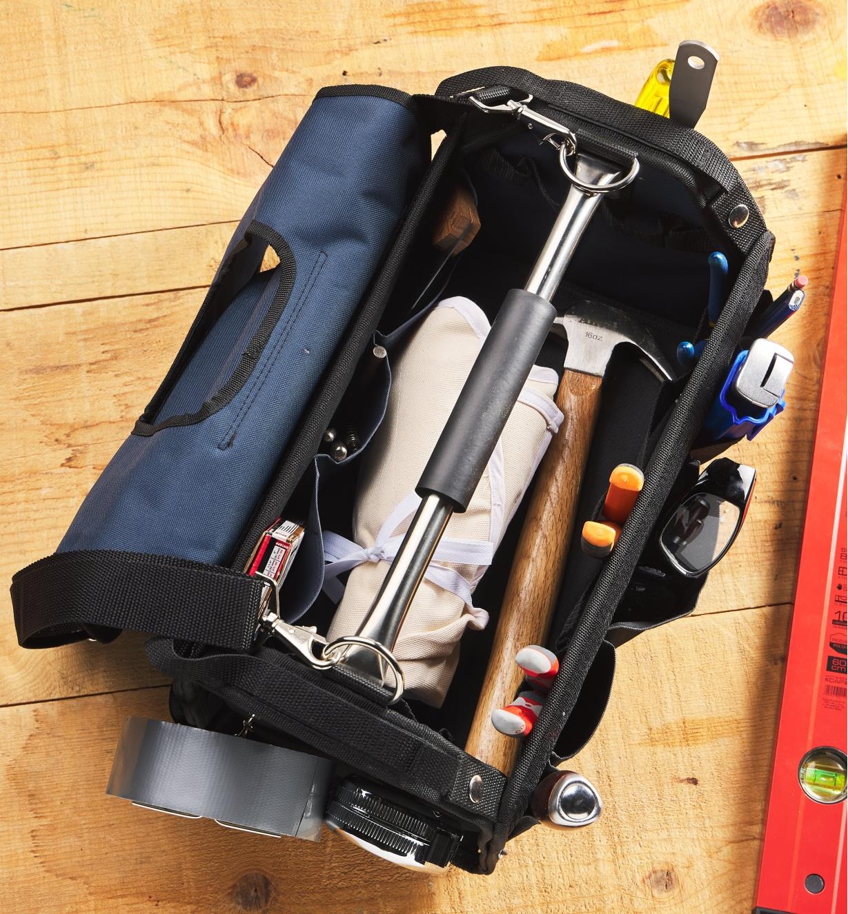 A carpenter’s tool bag seen from above with the cover removed and various tools inside and outside