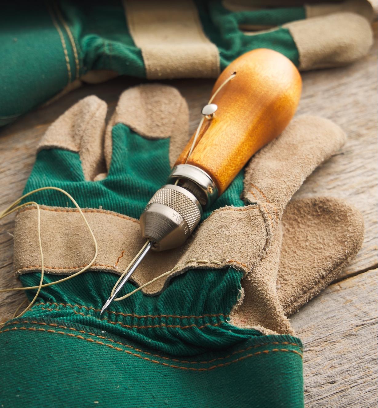 Ensemble de couture Speedy Stitcher déposé sur un gant de travail qui se fait réparer