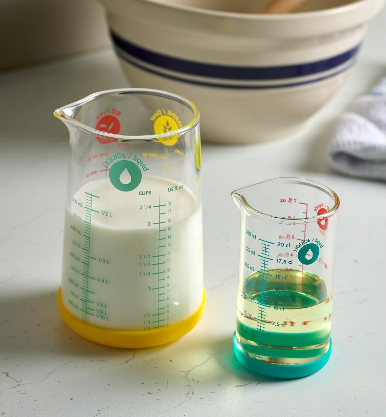 A 500ml measuring glass filled with milk next to a 200ml measuring glass filled with clear liquid