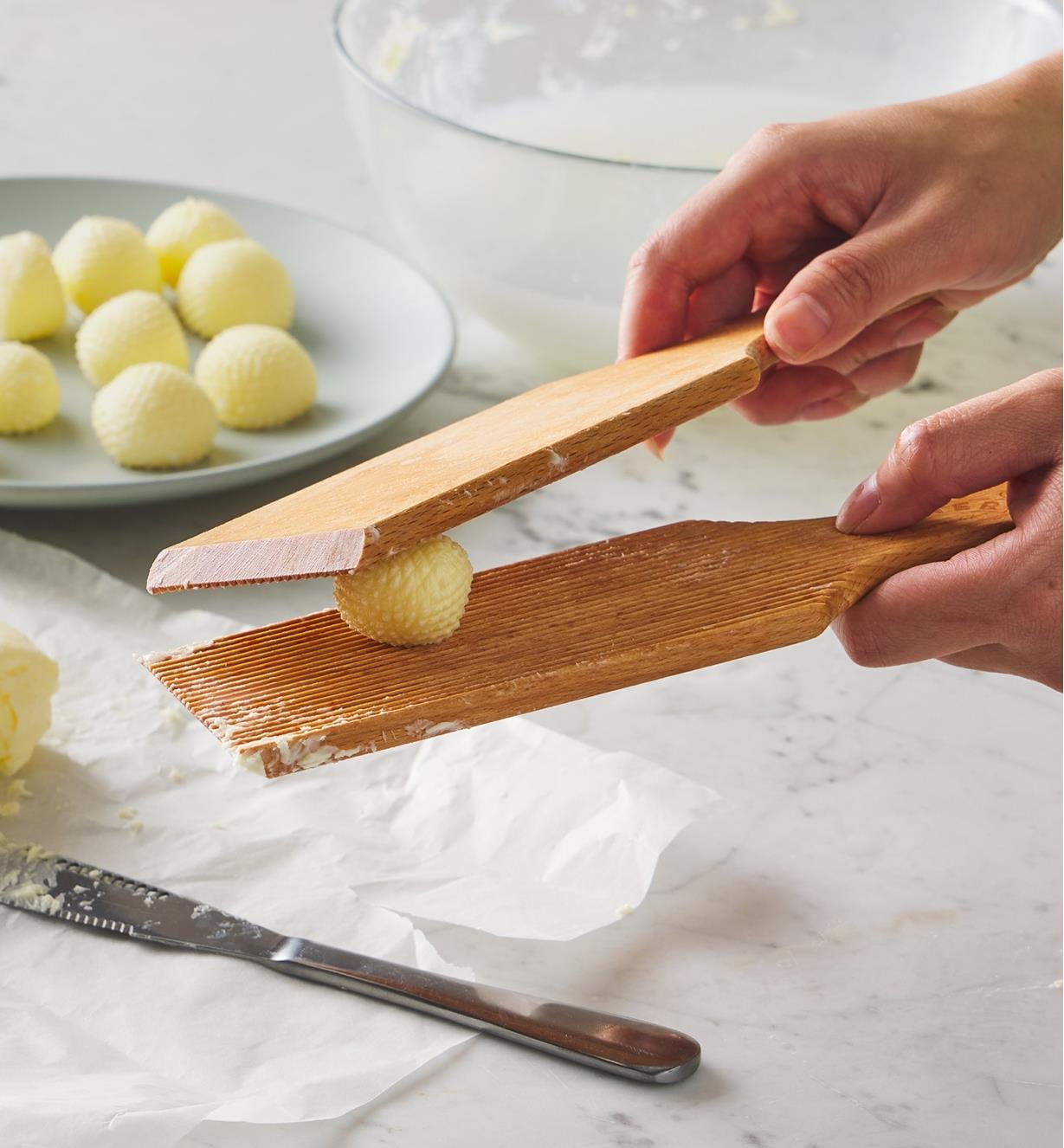 Two paddles being used to form a ball of butter