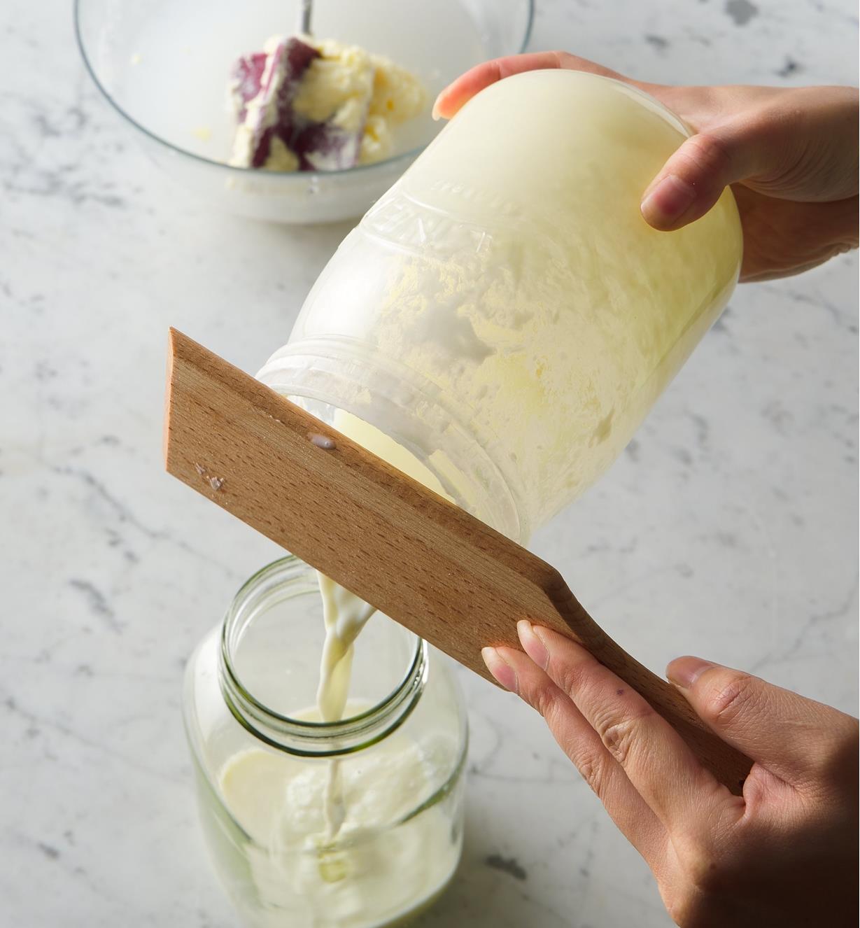Personne utilisant une palette à beurre pour laisser le babeurre s'écouler d'une baratte à manivelle