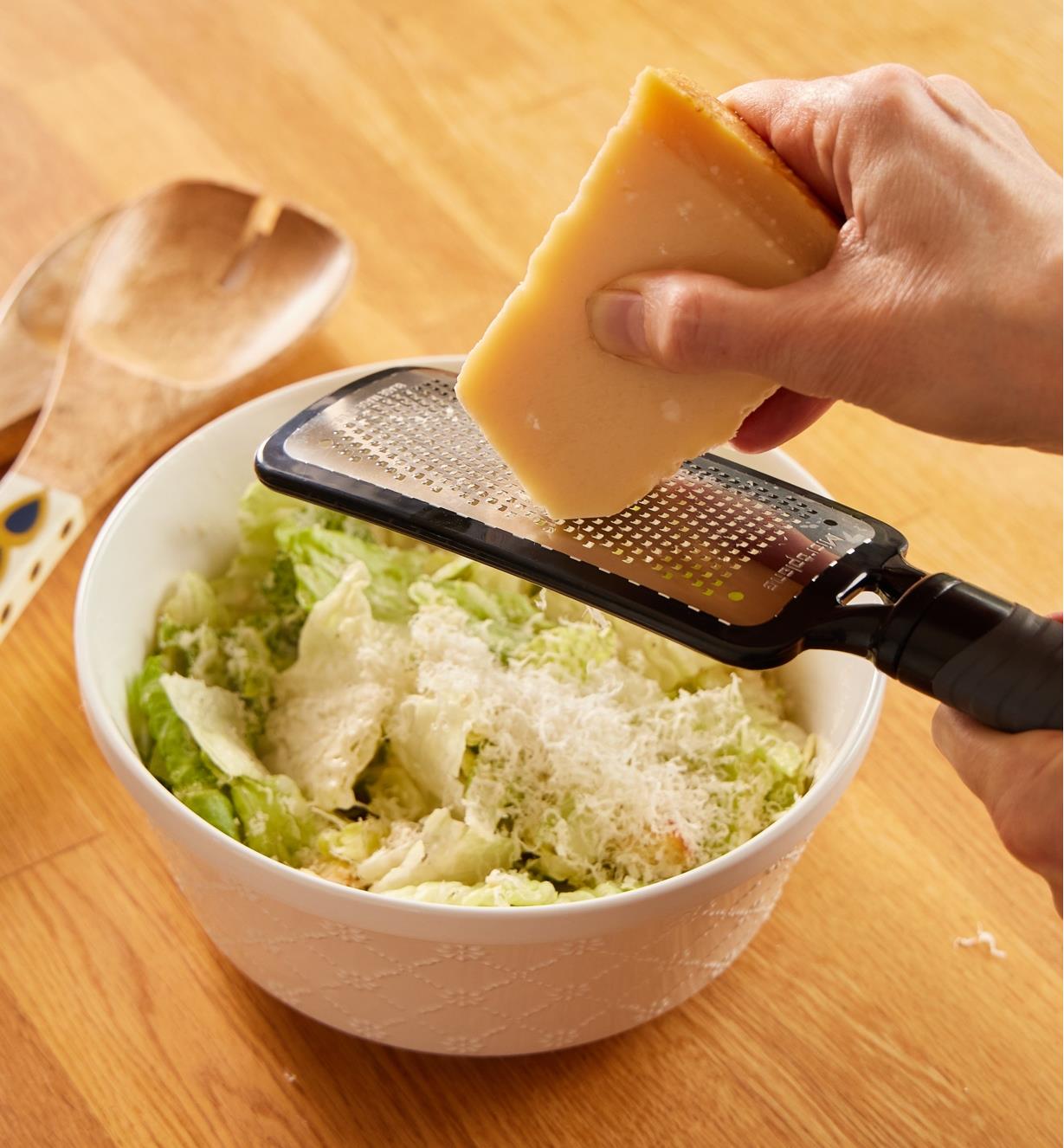 Using the fine paddle grater to grate hard cheese over a salad