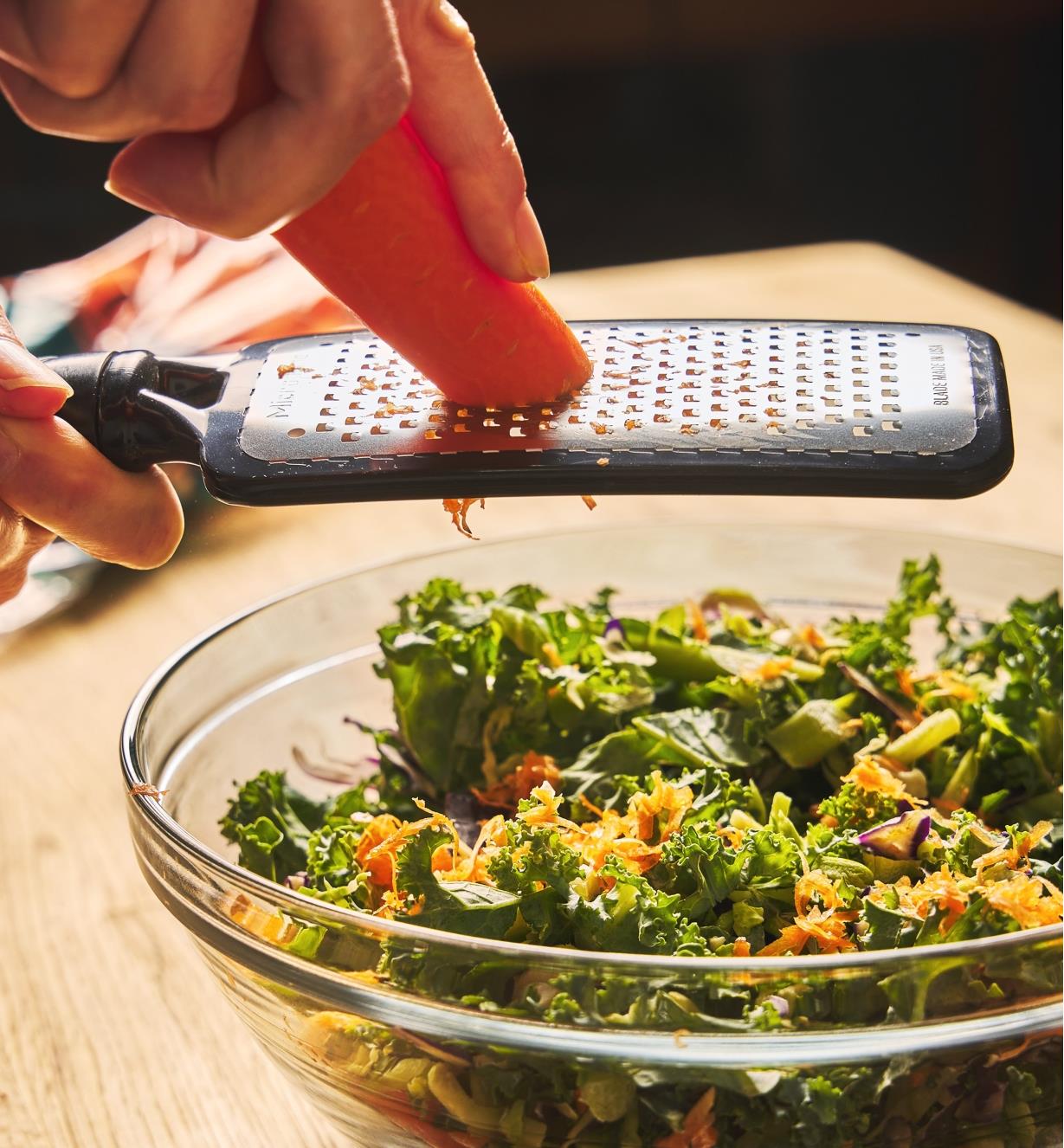 Using the coarse paddle grater to grate a carrot over a salad