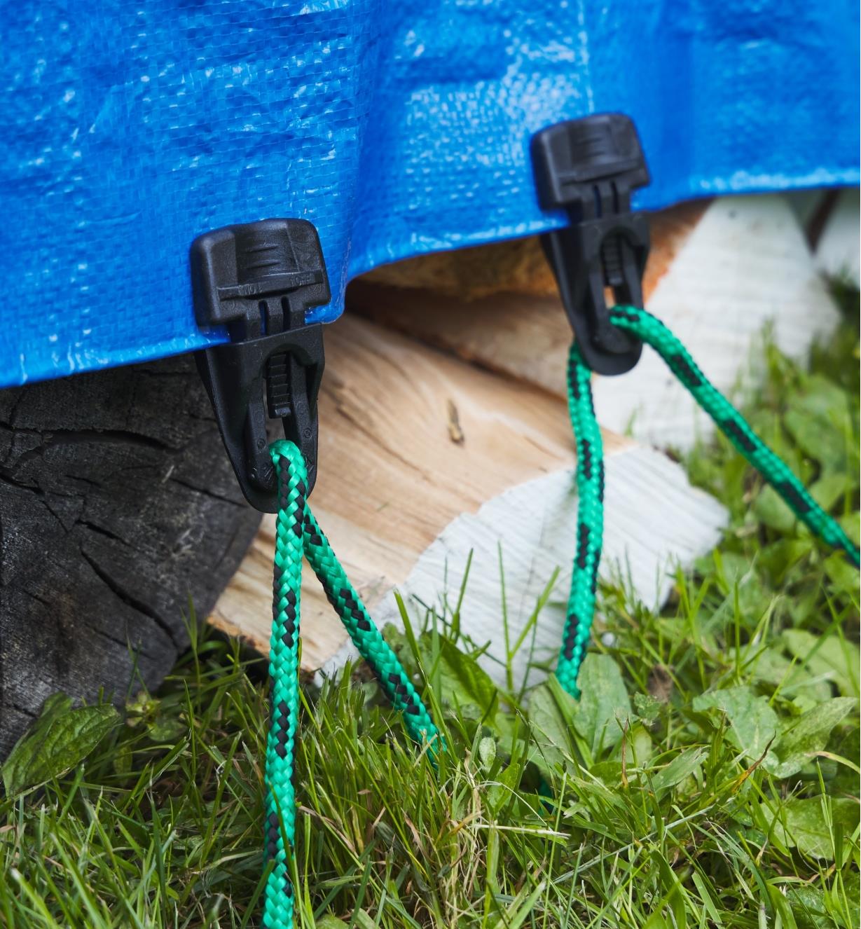 EasyKlip attached to a tarp covering chopped wood and secured to the ground with rope