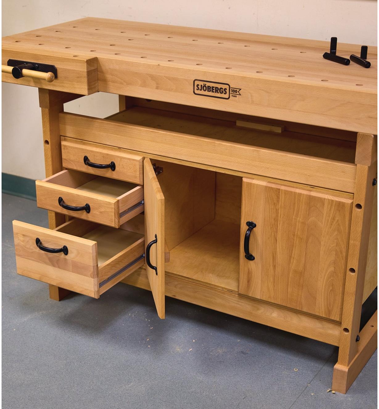 A workbench and storage module with the drawers and cupboard open on the module