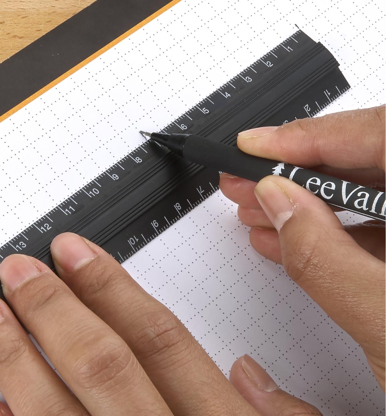 Personne utilisant une règle d'établi Veritas pour marquer une mesure sur un bloc de papier quadrillé Veritas