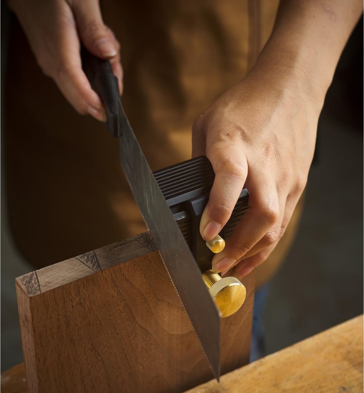 A Veritas Dovetail Guide clamped to a workpiece with someone about to make a cut with a saw