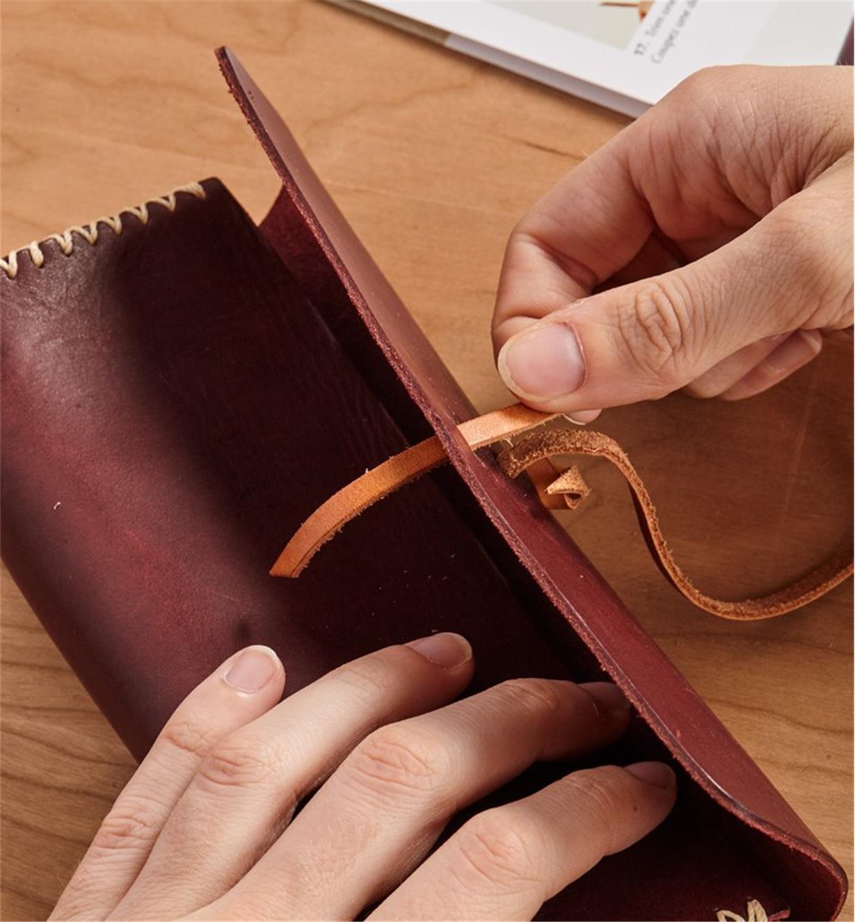 Feeding the leather cord through an opening in the leather case 