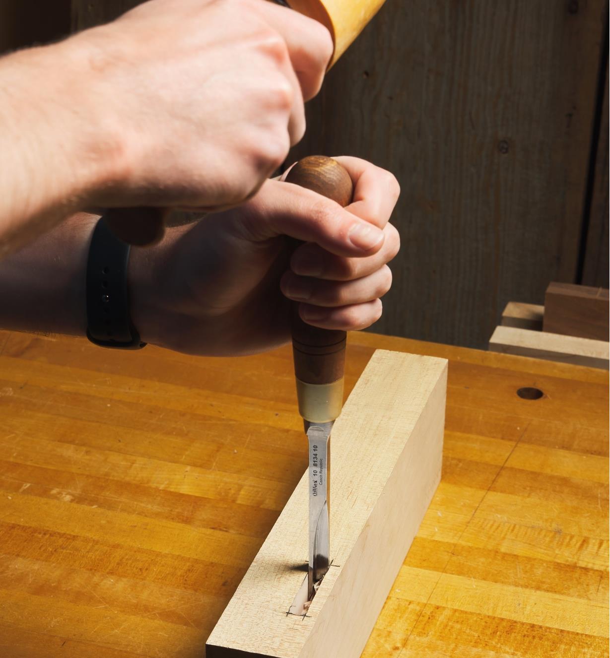 A corner chisel being used to square the corner of a mortise