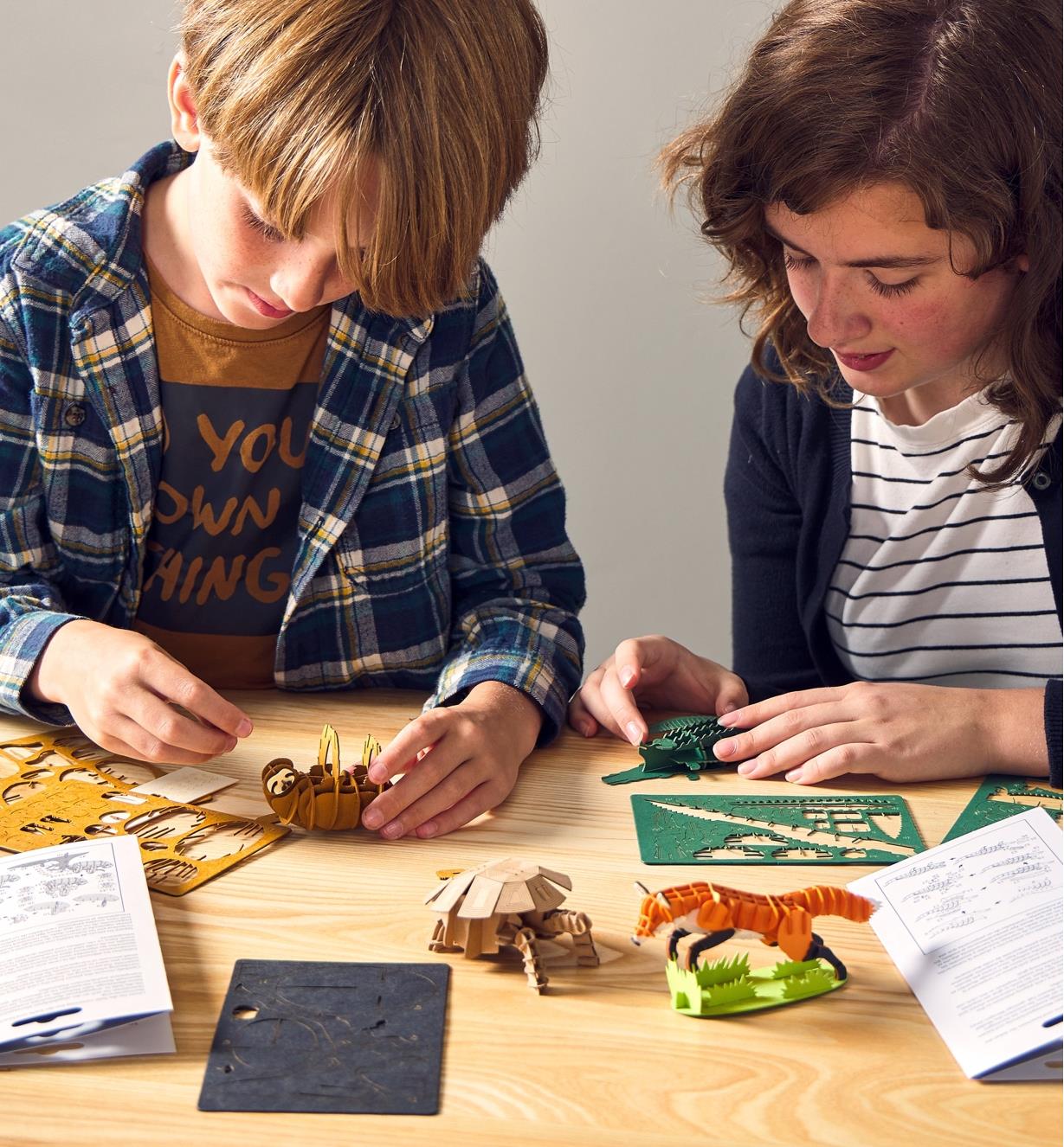 Two young people assemble paper animal models