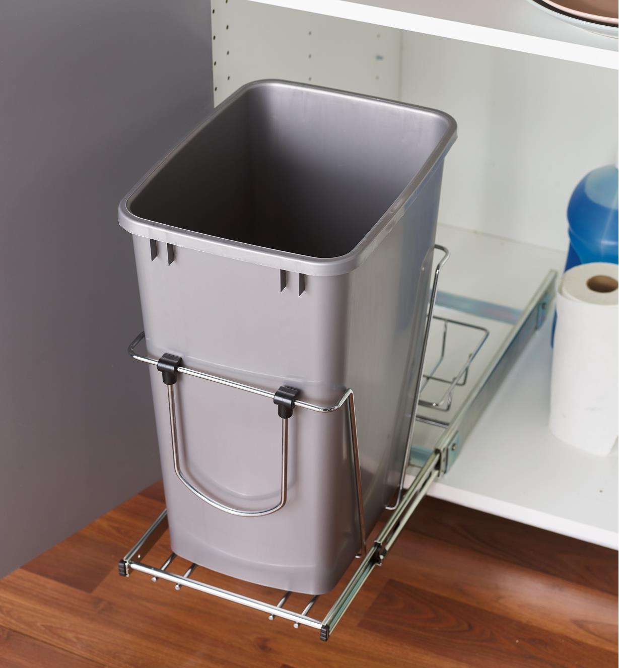 A rectangular plastic bin is secured on an extended slide in a cupboard
