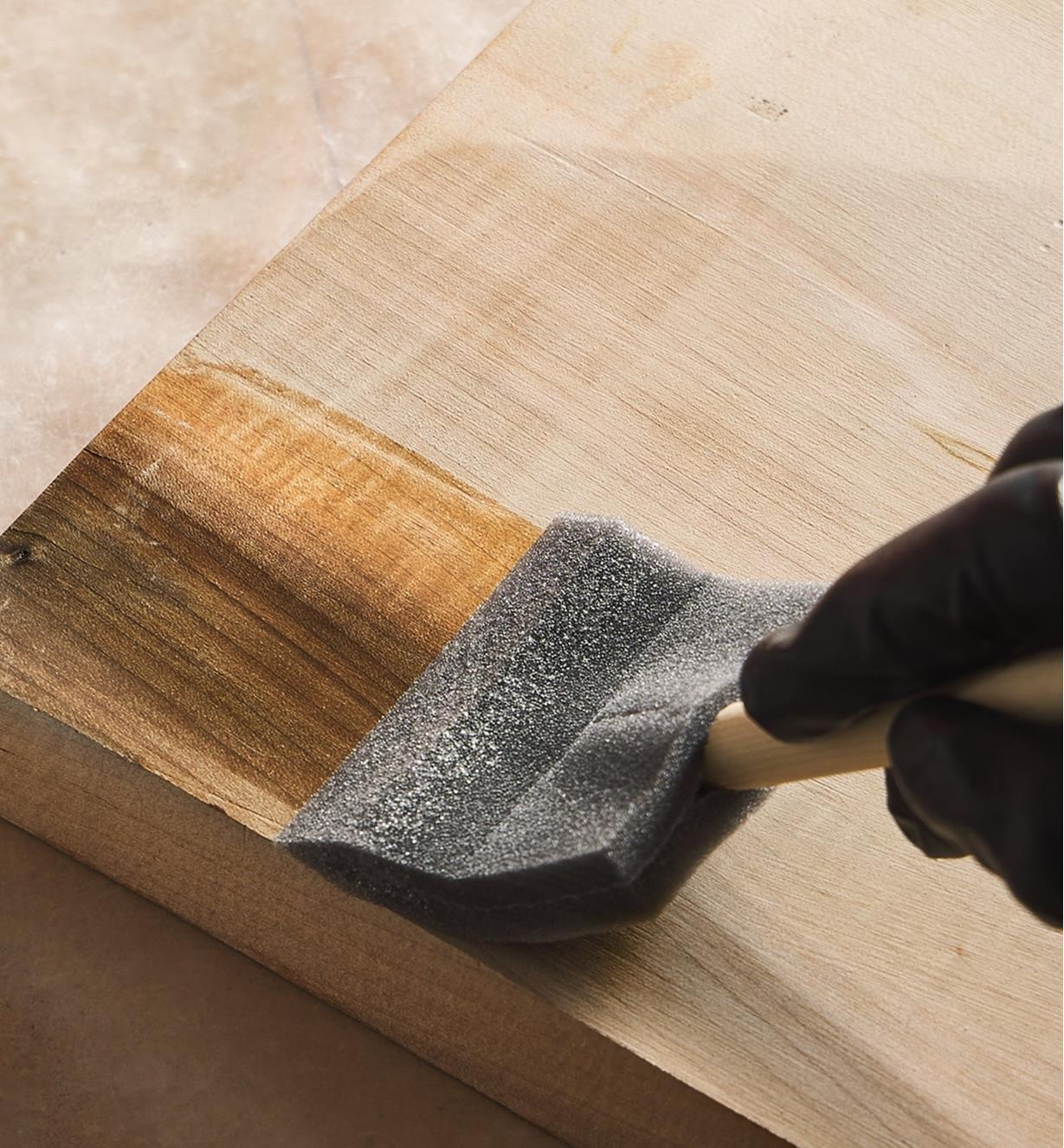 Applying wood bleach to a board using a foam brush